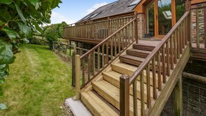 A wooden staircase leading to a glass door, surrounded by a stone wall and a wooden deck. - 3 Bed in Pontardawe (oc-c30415) (Cilybebyll Pontardawe)