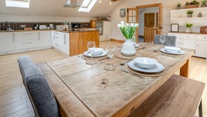 A modern kitchen with a wooden dining table set for four, a built-in oven, and a large window above the sink. - 3 Bed in Pontardawe (oc-c30415) (Cilybebyll Pontardawe)