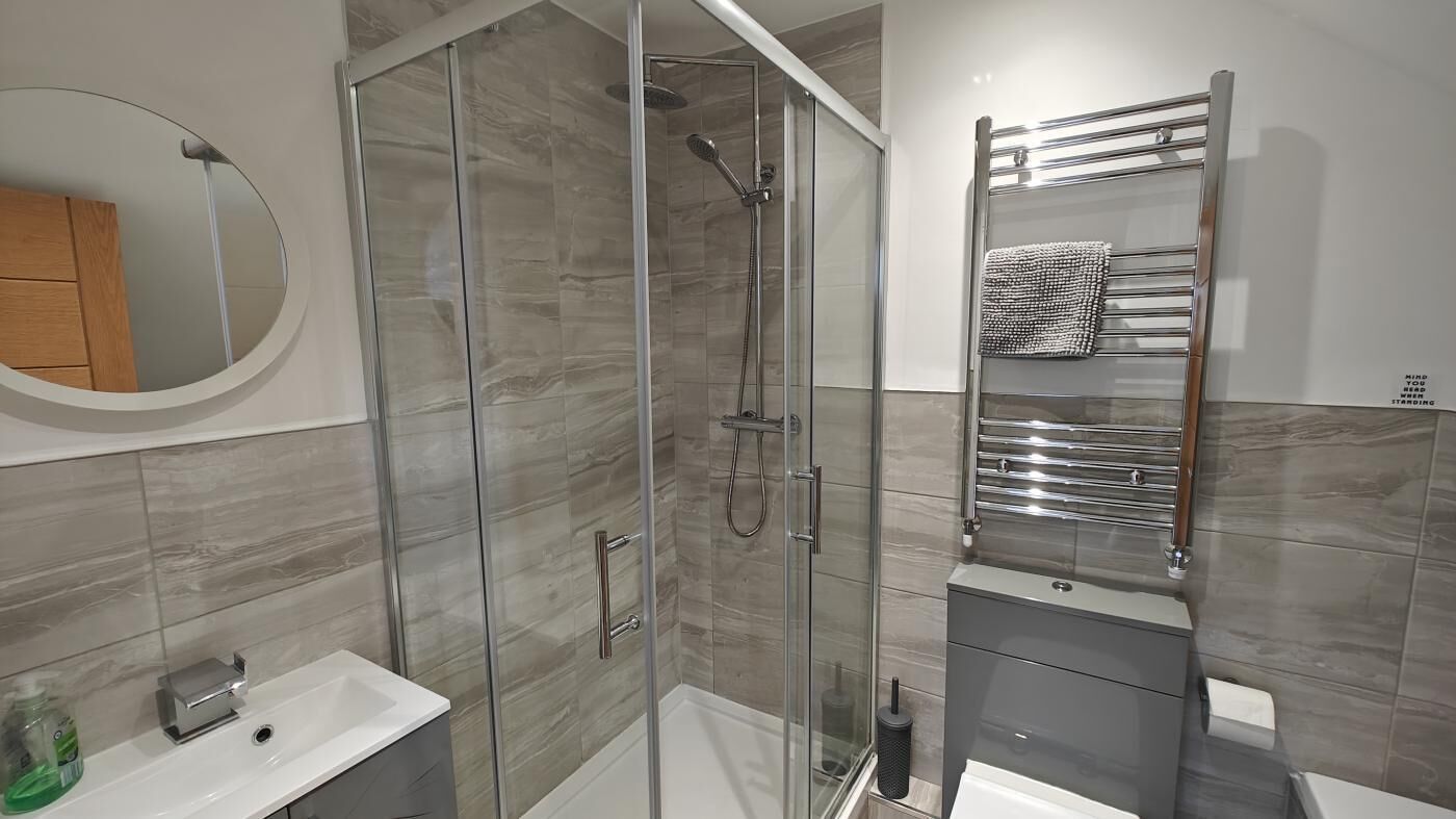 Une salle de bain moderne avec une douche à parois de verre, un meuble-lavabo avec un miroir et un porte-serviettes.