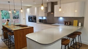 A modern kitchen with a central island, bar stools, and pendant lighting. - 7 Bed in Colintraive (oc-d30232) (Colintraive)