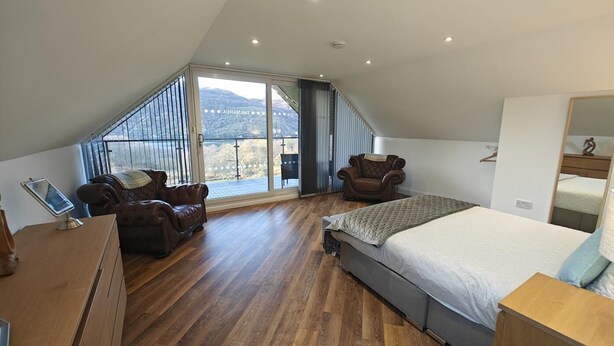 A bedroom with a large window, a bed, two leather armchairs, and a wooden desk. - 7 Bed in Colintraive (oc-d30232) (Colintraive)