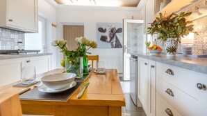 Una cocina moderna con armarios blancos, una mesa de comedor de madera y un florero con flores.
