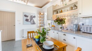 Una cocina moderna con armarios blancos, una mesa de comedor con platos, una cafetera y un tostador.