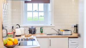 Eine Küche mit Fenster, Wasserkocher, Topf, Toaster und einer Obstschale.