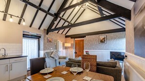 A dining area with a wooden table set for four, a sofa, and a kitchen area with a sink and cabinets. - 2 Bed in Hawsker (oc-c30335) (Stainsacre)