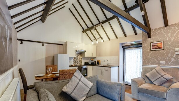 A cozy living room with a sofa and armchairs, a dining area with a table and chairs, and a kitchen with modern appliances. - 2 Bed in Hawsker (oc-c30335) (Stainsacre)