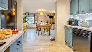 Une cuisine moderne avec un coin repas, comprenant une table en bois, des chaises et divers appareils de cuisine.