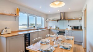 Una cocina moderna con una mesa de madera preparada para comer, un ventanal y vistas al exterior.