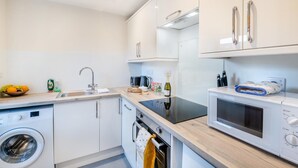 Una cocina moderna con lavadora, microondas y un lavamanos.