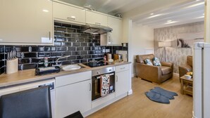Ett modernt kök med svarta och vita kakelplattor, en inbyggd ugn och en matplats med en soffa i läder och ett litet bord.