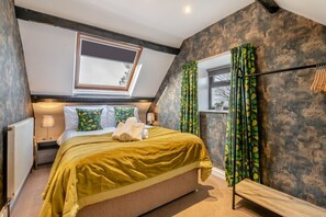 A bedroom with a sloped ceiling, a bed with a yellow bedspread, a skylight, and a window with patterned curtains. - 2 Bed in Stainsacre (oc-m30328) (Stainsacre)