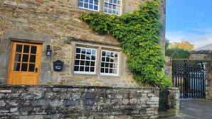 A stone building with ivy climbing up the side, a wooden door, and a black sign with "Inn" written on it. - 2 Bed in West Burton (oc-i30367) (West Burton)