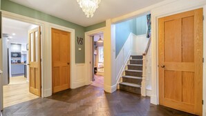 Ein Korridor mit Holztüren, einer Treppe und einem Kronleuchter.