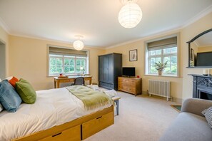 A bedroom with a bed, desk, wardrobe, TV, fireplace, and large windows. - 5 Bed in Church Stretton (oc-t30413) (Church Stretton)