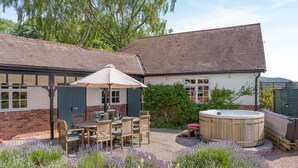 A patio with a table and chairs, a hot tub, and a garden with lavender. - 5 Bed in Church Stretton (oc-t30413) (Church Stretton)