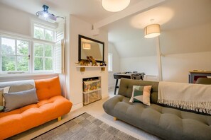 A living room with two sofas, a fireplace, a mirror, and a window with a view of trees. - 5 Bed in Church Stretton (oc-t30413) (Church Stretton)