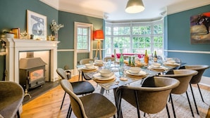 A dining room with a fireplace, a large window, and a table set for six. - 5 Bed in Church Stretton (oc-t30413) (Church Stretton)