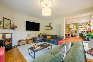 Una sala de estar con chimenea, sofá, mesa de centro y televisor.