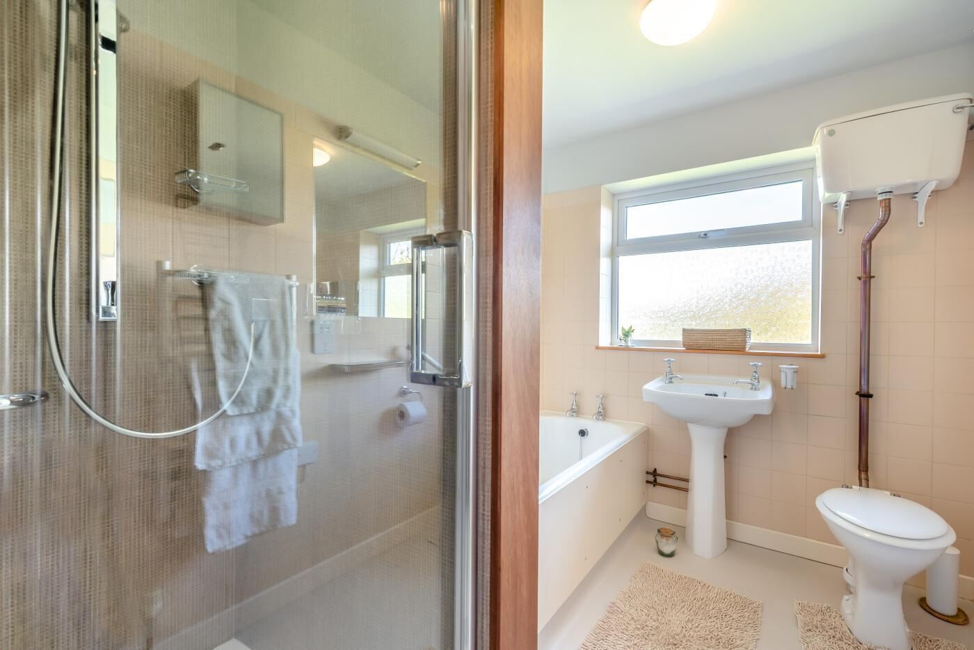 Een badkamer met een douchecabine van glas, een witte wastafel, een bad en een toilet.