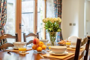 Ein Esstisch mit Früchten, einer Blumenvase und einem Teller mit Croissants.
