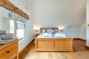 Ein Schlafzimmer mit einem hölzernen Bett, Nachttischlampen, einem Fenster mit Blick und einer Holzkommode.