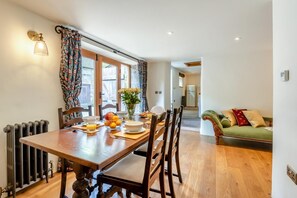 A dining area with a wooden table, chairs, a vase with flowers, and a view to the outside. - 2 Bed in Onecote (oc-r30424) (Onecote)