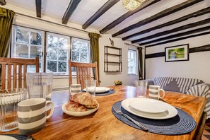 A dining area with a wooden table, chairs, and a sofa. - 2 Bed in Woodchurch (oc-b30323) (Woodchurch)
