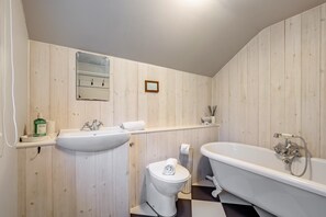 A bathroom with a sink, toilet, and bathtub, wooden panel walls, and a small shelf with toiletries. - 2 Bed in Woodchurch (oc-b30323) (Woodchurch)