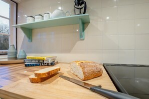 Une cuisine équipée d’une planche à découper, d’une miche de pain, d’un couteau et d’une pile de livres de recettes.
