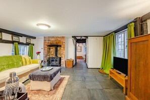 A living room with a sofa, a table, a TV, a fireplace, and a hallway leading to another room. - 2 Bed in Woodchurch (oc-b30323) (Woodchurch)