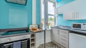 Et moderne køkken med teal vægge, hvide skabe, en indbygget ovn, en mikroovn og en brødrister.
