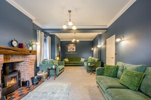 A living room with a fireplace, green sofas, a coffee table, and a rug.