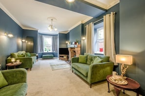 A living room with a fireplace, green sofas, a coffee table, and a lamp.