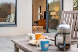 A cozy outdoor seating area with a table set for breakfast, a coffee pot, and a view of the interior through a glass door. - 5 Bed in Corfe Castle (oc-r30456) (Corfe Castle)