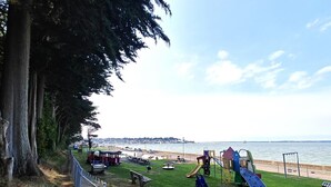 A park with playground equipment, benches, and a view of the sea. - 2 Bed in East Cowes (oc-h30421) (East Cowes)