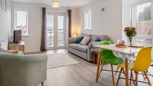 A modern living room with a sofa, a dining table with chairs, and a television on a stand. - 2 Bed in East Cowes (oc-h30421) (East Cowes)