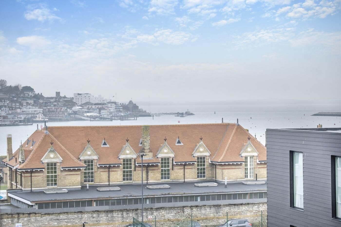 Um edifício costeiro com telhado em telhas, várias chaminés e fachada de pedra.