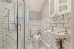 A bathroom with white subway tiles, a glass shower enclosure, a toilet, and a sink with a mirror above. - 3 Bed in Uploders (oc-g30276) (Uploders)