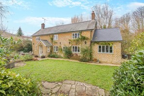 A stone house with a grassy yard, a small porch, and a chimney. - 3 Bed in Uploders (oc-g30276) (Uploders)