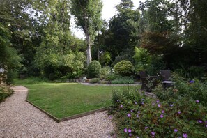 A well-maintained garden with a lawn, gravel path, and outdoor seating area. - 3 Bed in Uploders (oc-g30276) (Uploders)
