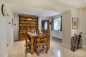 A dining area with a wooden table and chairs, a wine rack, and a clock on the wall. - 3 Bed in Uploders (oc-g30276) (Uploders)