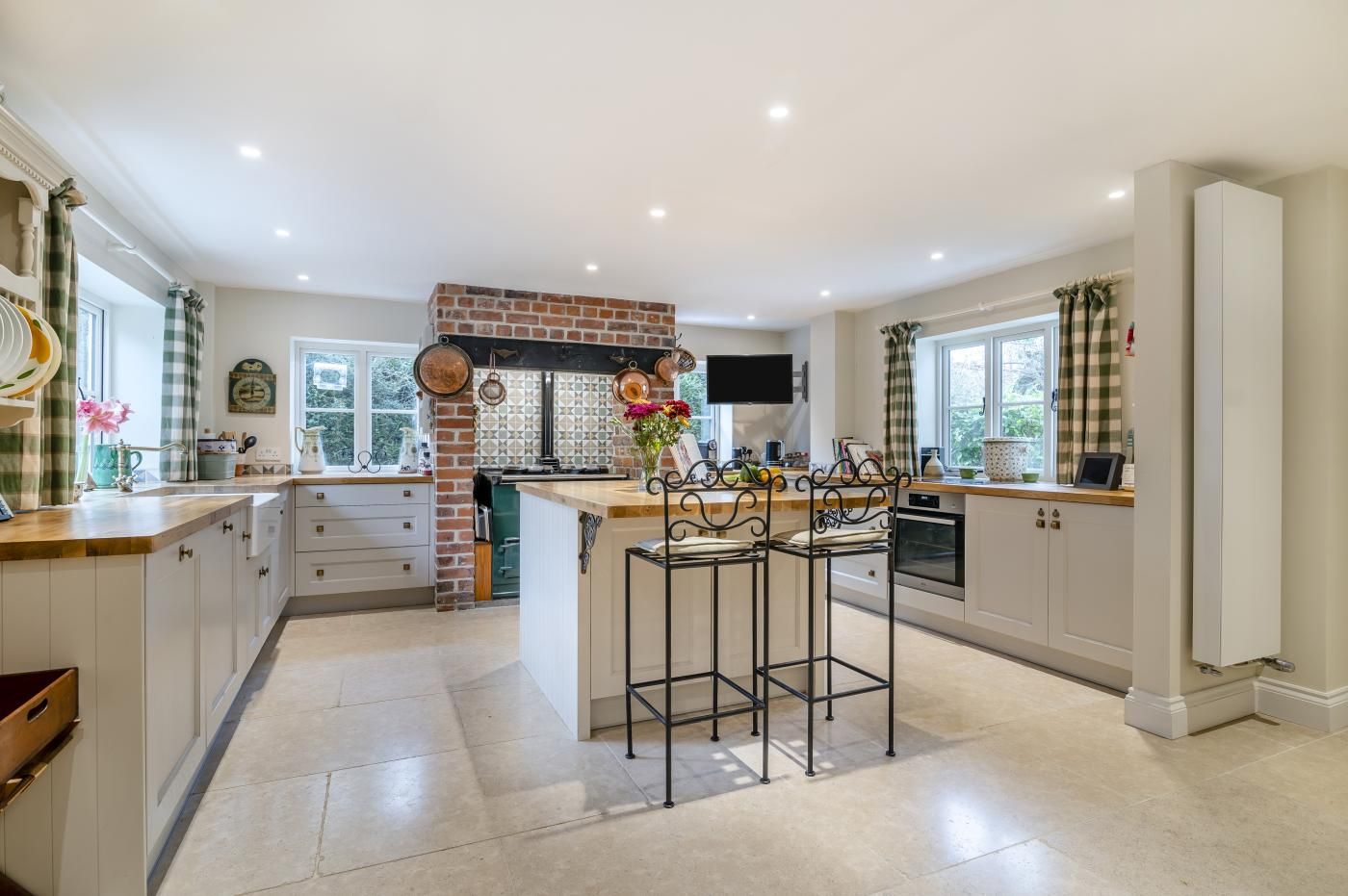 A spacious kitchen with a central island, white cabinetry, and a brick backsplash.