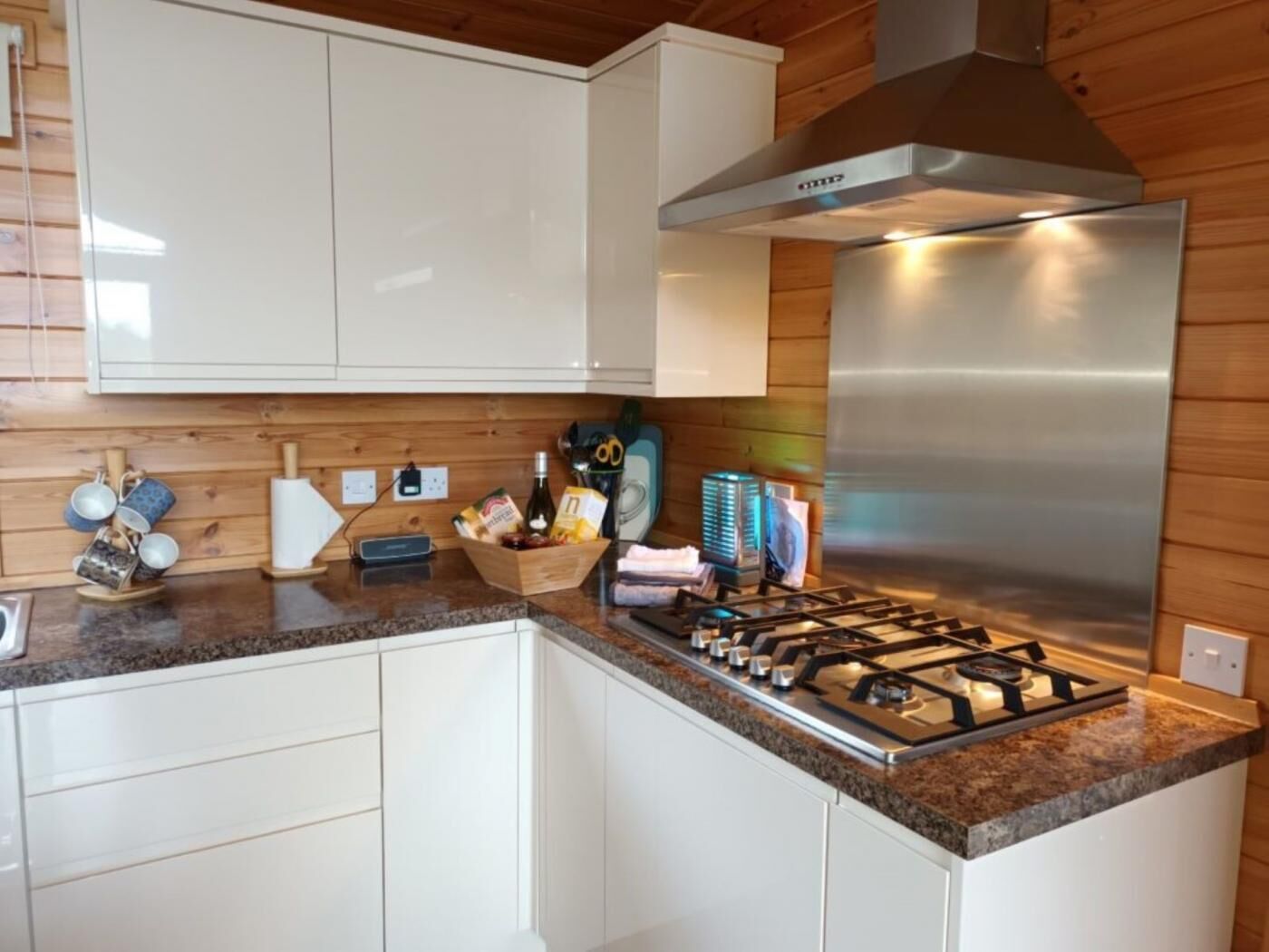 A modern kitchen with white cabinets, a stainless steel range hood, and a granite countertop.