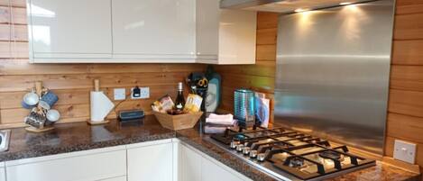 A modern kitchen with white cabinets, a stainless steel range hood, and a granite countertop.