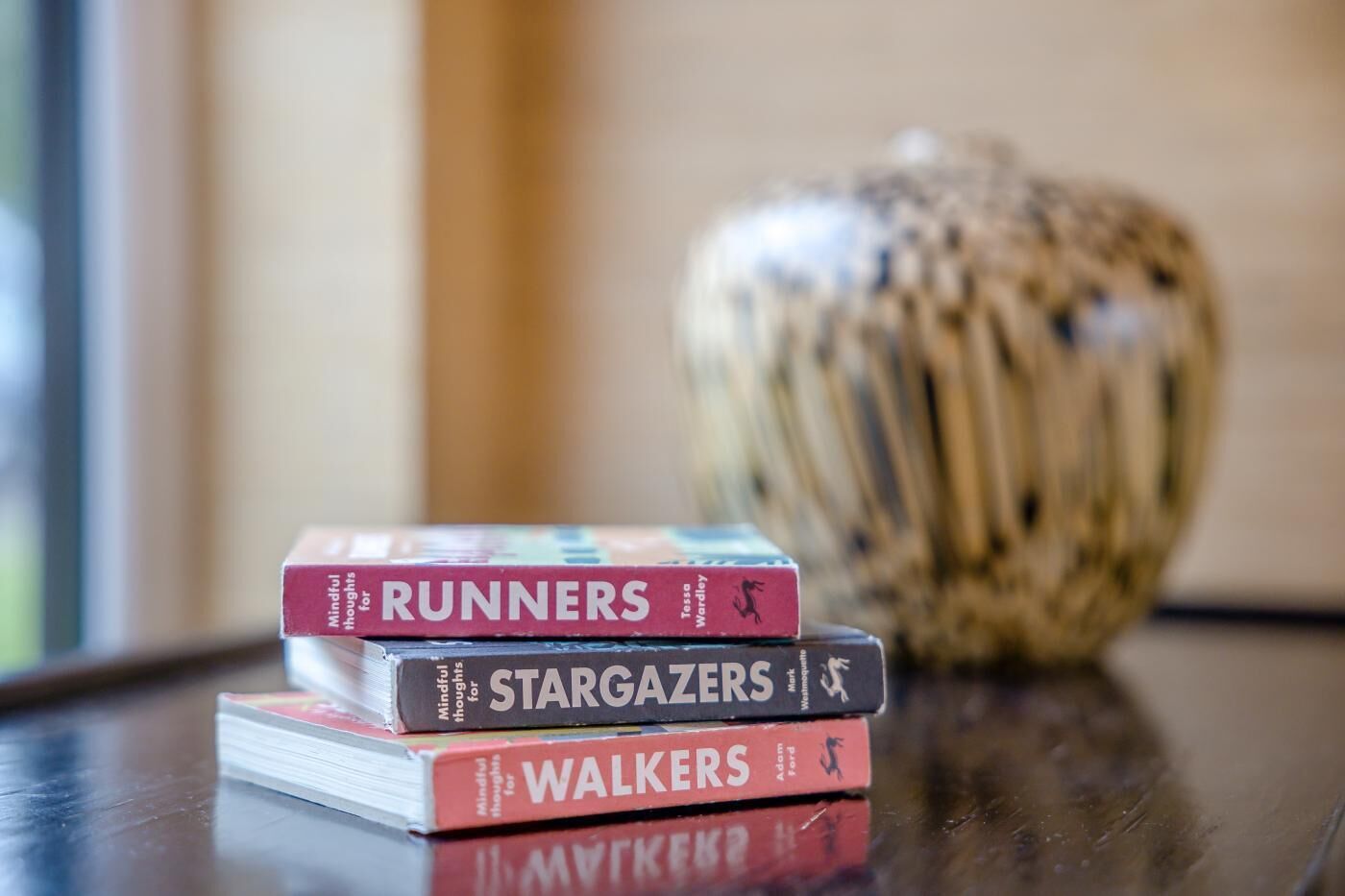 A stack of books titled 'Runners,' 'Stargazers,' and 'Walkers' on a table.