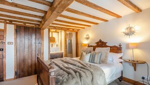A bedroom with a wooden bed, a large mirror, and a nightstand with a lamp.