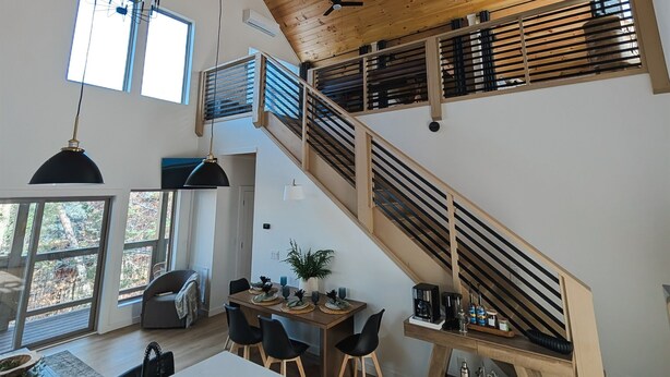 Eine geräumige Küche mit einer Holztreppe, einem Essbereich mit Blick ins Freie und einer modernen Pendelleuchte.