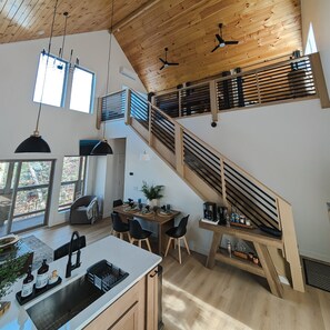A spacious kitchen with a wooden staircase, a dining area with a view of the outdoors, and a modern pendant light. - Fall Sale • Pigeon Forge Fun • 2 Kings + Bunks (Pigeon Forge)
