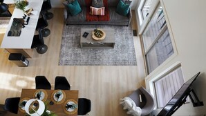 Ein modernes Wohnzimmer mit grauem Sofa, Couchtisch und Essbereich mit Holztisch und Stühlen.