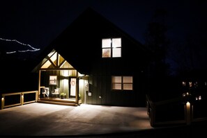 Ett hus med en stor entrédörr av glas, en synlig interiör med ett matbord och stolar samt en liten veranda.